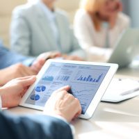 Business person analyzing financial statistics displayed on the tablet screen.
